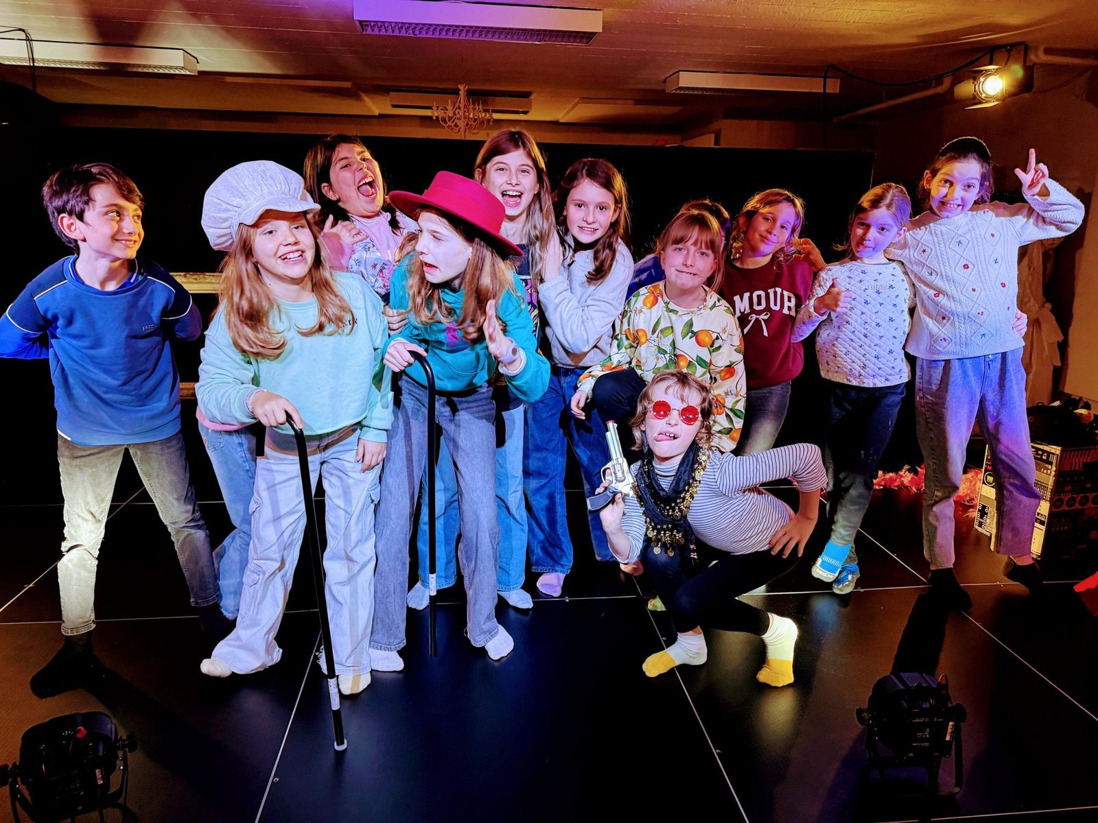 Un groupe d'enfants costumés sur scène, bras levés, à la fin d'une représentation