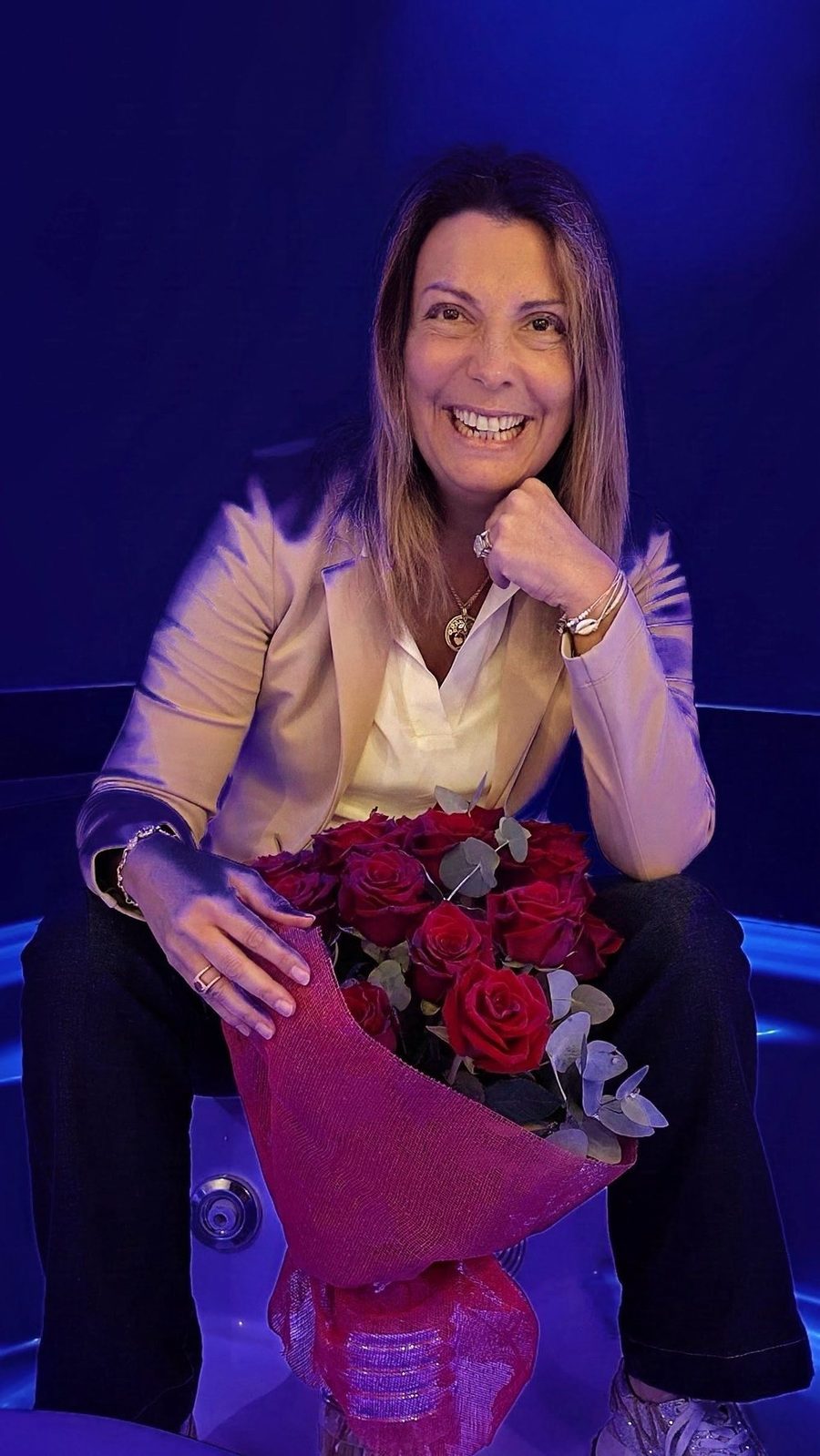 Danielle Fougerouse, souriante, assise sur scène avec un bouquet de roses